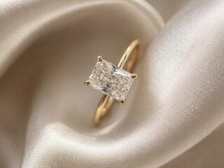 Anillo de compromiso con diamante corte radiante sobre tela de satín