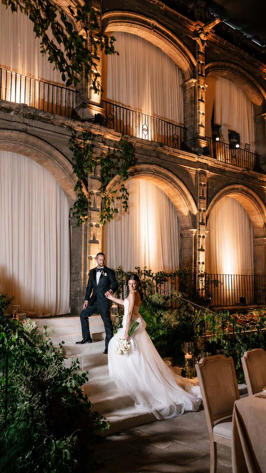 Novios en el patio iluminado de una hacienda colonial con arcos y cortinas