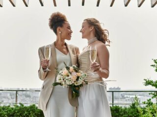 Dos novias brindan con champaña en una terraza con vista a la ciudad