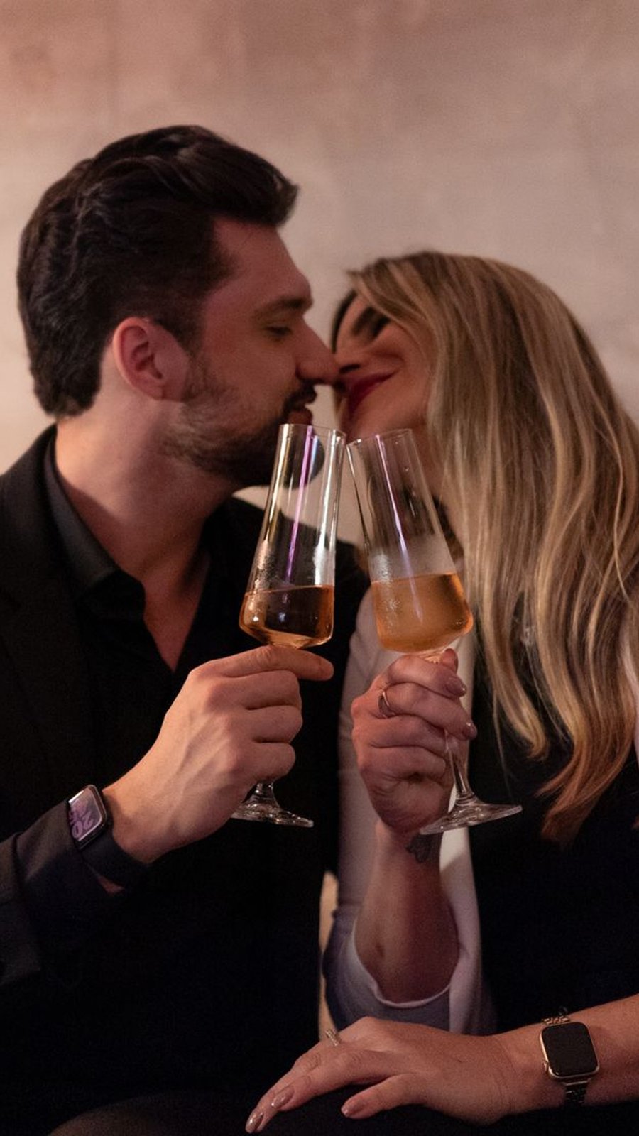 Pareja se besa mientras brinda con copas de vino