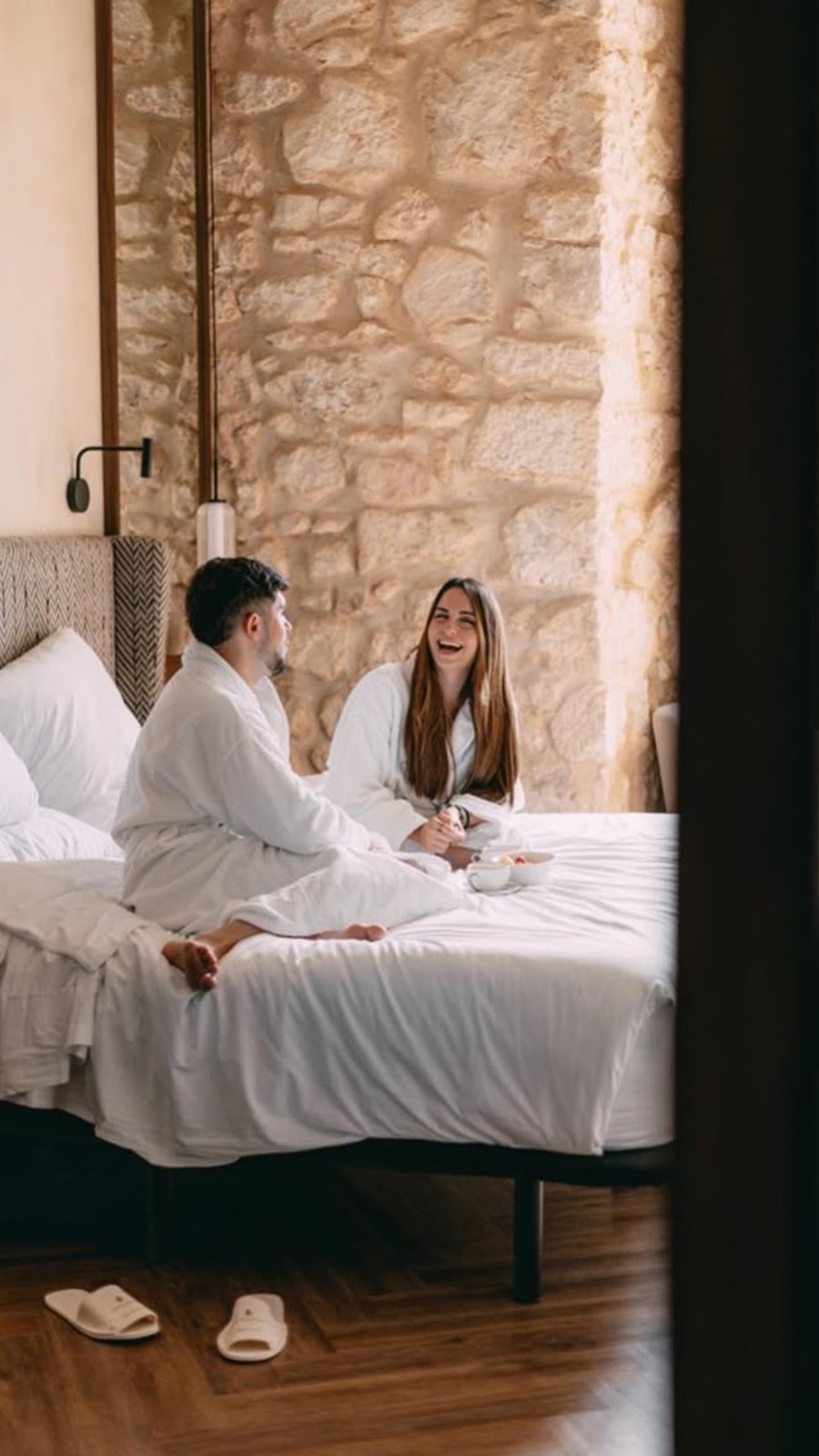 Pareja en bata en la habitación de un hotel con muros de piedra