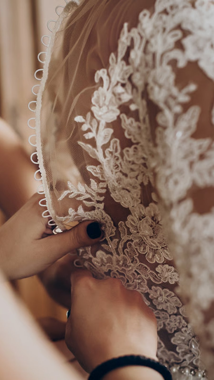 Manos abotonan la espalda de encaje del vestido de novia