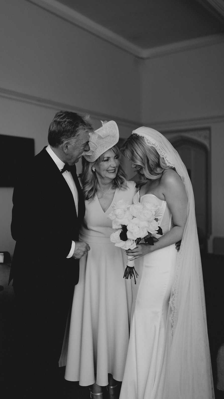 Novia abrazada por sus padres, en blanco y negro