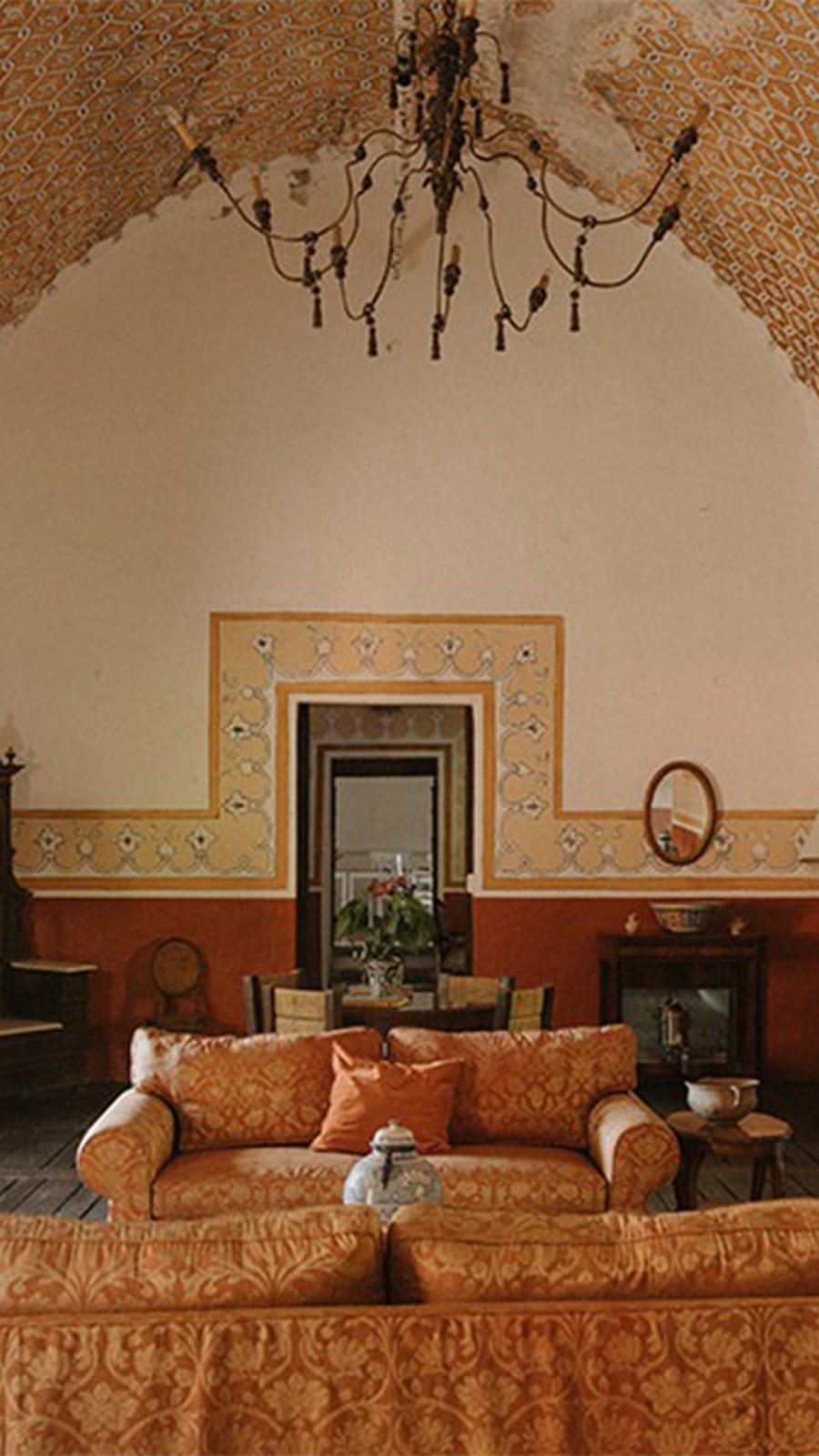 Sala de una hacienda con candil de hierro y muros decorados, parte del hospedaje