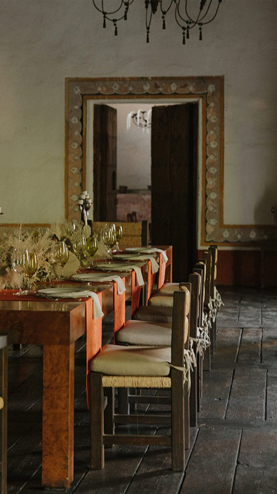 Comedor de hacienda con mesa larga, sillas tejidas y centros de flores secas