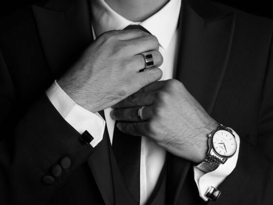 Novio se ajusta la corbata con reloj y anillo en primer plano, en blanco y negro