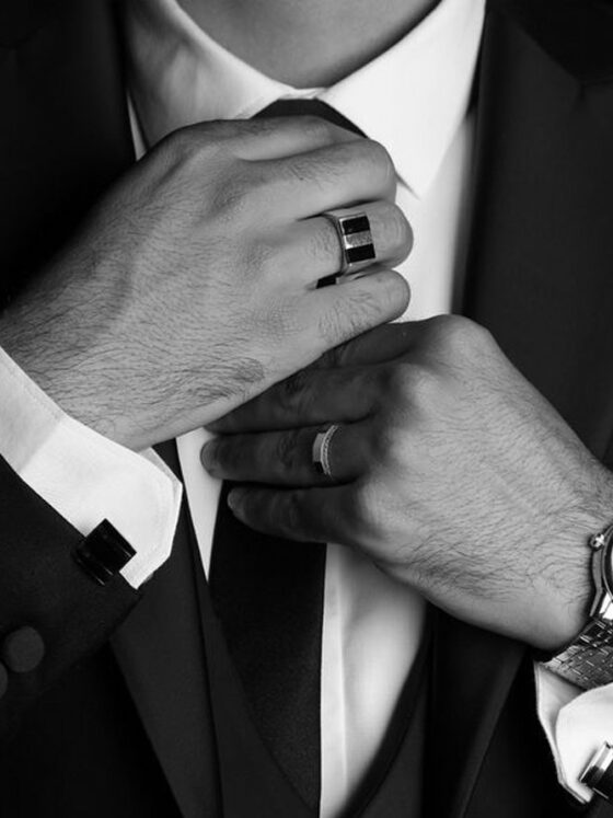 Novio se ajusta la corbata con reloj y anillo en primer plano, en blanco y negro
