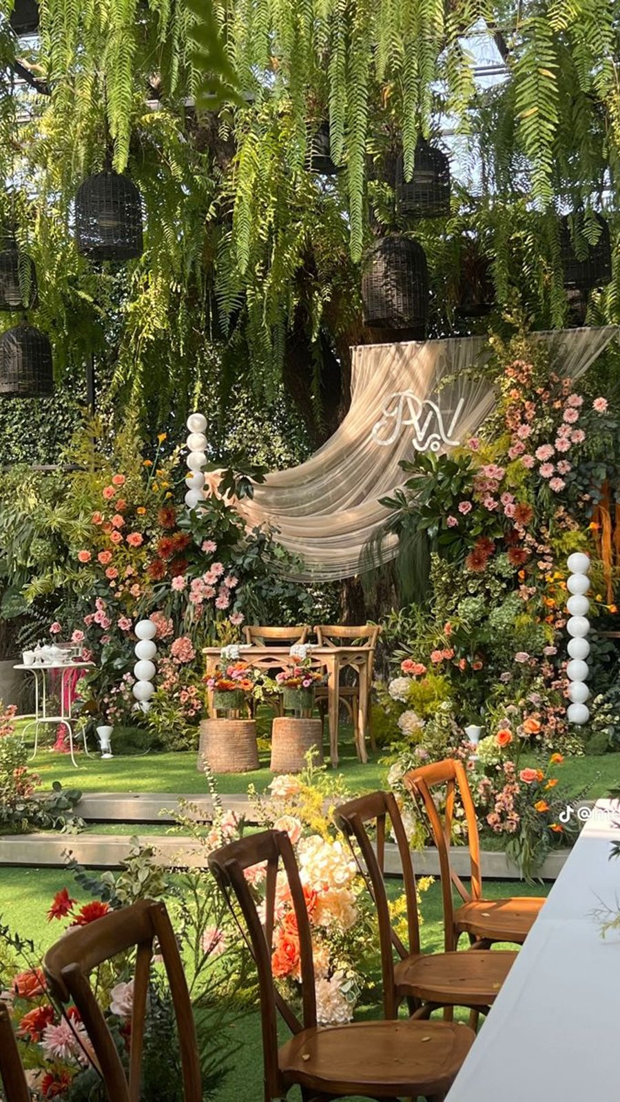Jardín con arco floral, telas y sillas de madera para una boda estilo cottagecore