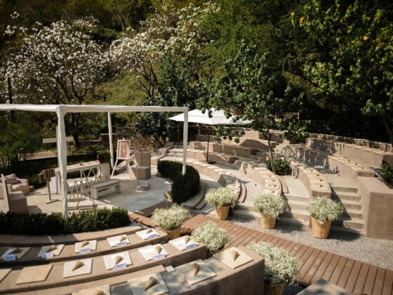Montaje de ceremonia con gradas de madera en un jardín rodeado de vegetación