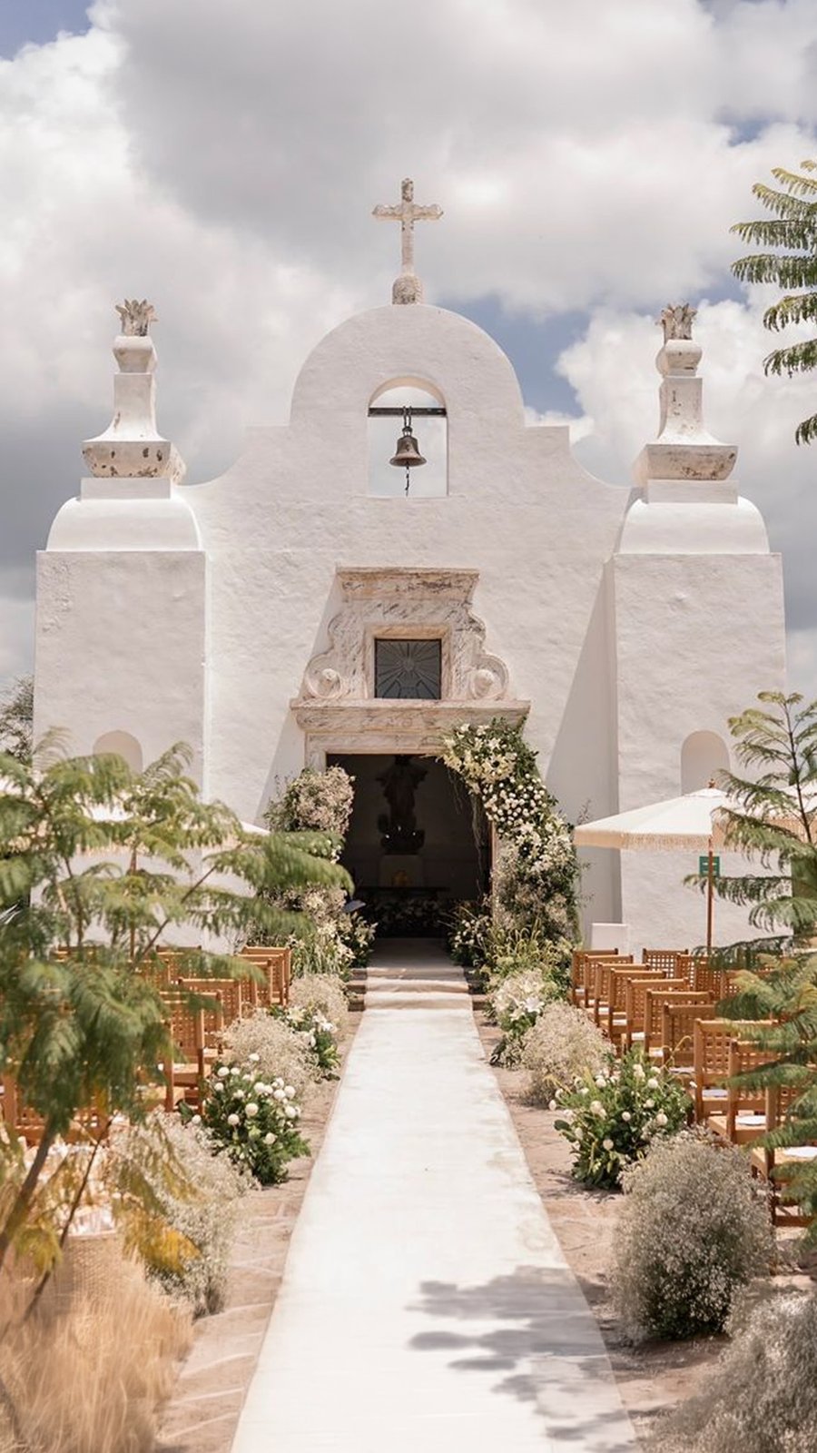 Capilla blanca con pasillo decorado con plantas y flores para la ceremonia
