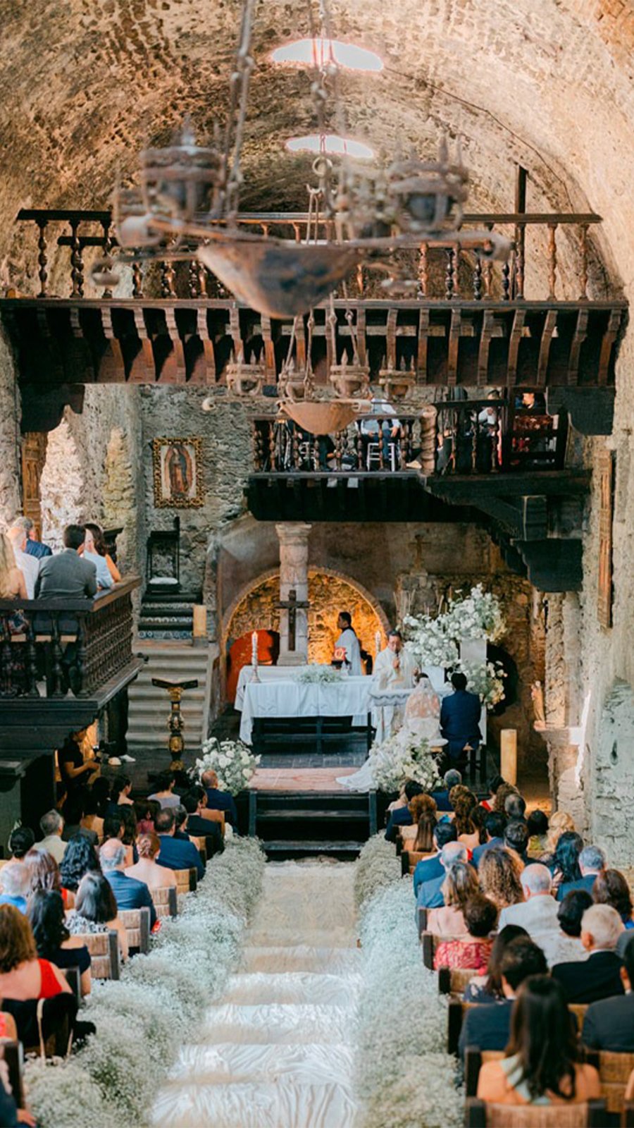 Ceremonia religiosa en una capilla antigua con pasillo de flores blancas