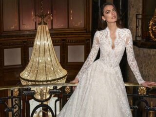 Novia con vestido de encaje de manga larga y escote en V en un salón con candil